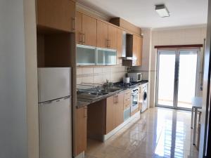 cocina con armarios de madera y nevera blanca en Nazaré Beach Apartments, en Nazaré