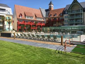 a group of chairs sitting in the grass next to a building at Cyrille et Vacances Presqu'ile de la Touques in Deauville