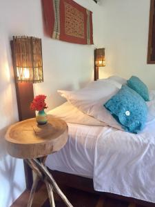 Una cama con almohadas azules y una mesa al lado. en Cumelen, en Jericoacoara