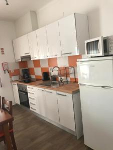 a kitchen with white cabinets and a white refrigerator at Zesty Orange by ITHOUSE in Albufeira