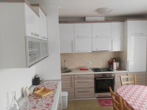 a kitchen with white cabinets and a table and a dining room at Apartmani Janjic in Banja Luka