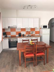 a kitchen with a wooden table and chairs and a kitchen with white cabinets at Zesty Orange by ITHOUSE in Albufeira