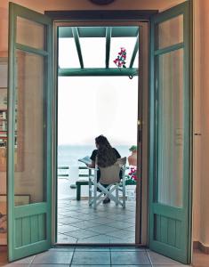 a woman sitting in a chair on a balcony looking at the ocean at Plori House in Skiros