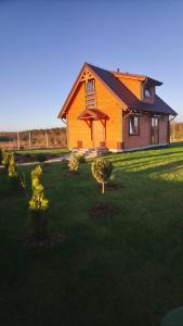 a yellow house with a yard with trees in front of it at Lavender Cottage in Charzykowy