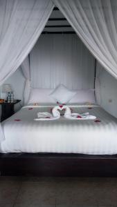 a large white bed with two towels on it at Puri Sunset Homestay in Munduk