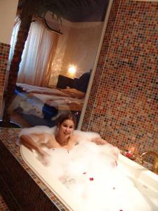 Una donna sdraiata nella vasca da bagno in una camera da letto di Gasthof Kemmetmüller a Windischgarsten