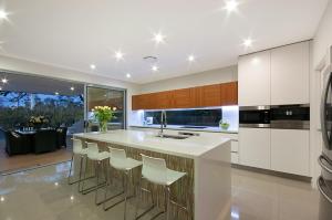 a kitchen with white cabinets and a counter with stools at Hidden Paradise in Gold Coast