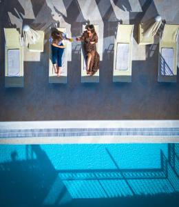 two women sitting on chairs next to a swimming pool at Hotel Kadmo by Aycon in Budva