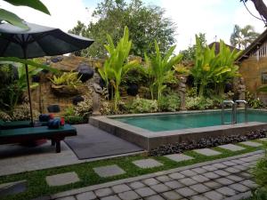 einen Pool in einem Garten mit Sonnenschirm in der Unterkunft Sari Mimpi Kutuh in Ubud