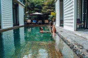 two children sitting in the water in a swimming pool at Silver Urban in Siem Reap