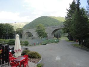 eine Brücke über eine Straße mit Stühlen und einem Regenschirm in der Unterkunft Residence Il Mulinaccio in Pievepelago