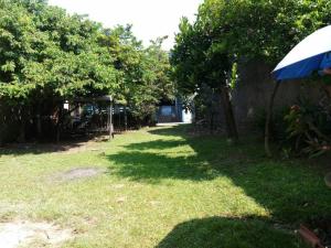 un patio con sombrilla y hierba y árboles en Seventeen homestay, en Bandung
