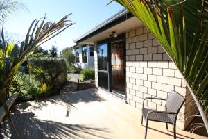 un patio con una sedia e una casa di The Red Hen And Dog a Ohope Beach