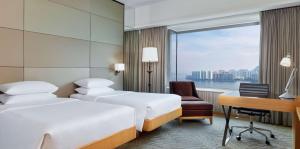 a hotel room with two beds and a desk and a window at Hyatt Regency Hong Kong, Sha Tin in Hong Kong