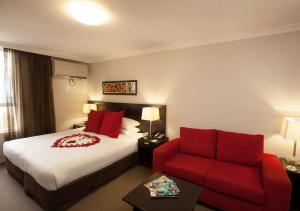 a hotel room with a bed and a red couch at Wine Country Motor Inn in Cessnock