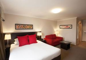 Habitación de hotel con cama y silla roja en Wine Country Motor Inn, en Cessnock