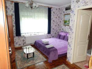 a bedroom with a purple bed and a window at Budai Panzió in Székesfehérvár