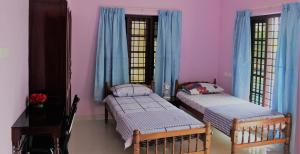 two beds in a room with pink walls at Puthenchirayil Homestay in Trivandrum