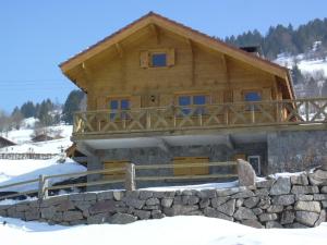 a log cabin in the snow with a stone wall at Chalet Helalph in La Bresse