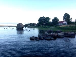 a river with rocks and a house in the distance at Merekalda Accommodation - Adults Only in Käsmu