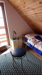 a bedroom with a bed and a chair in a room at Lavender Cottage in Charzykowy