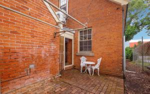 a patio with two chairs and a table in a brick building at Eliza 1875 Red Brick Duplex Townhouse in Grafton