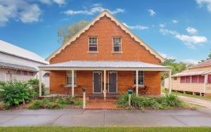 a red brick house with a porch on a street at Azile 1875 Heritage Victorian Duplex in Grafton