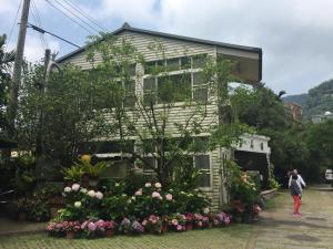 a house with flowers in front of it at Yu Ho Yuan Lesiure Homestay in Nanzhuang