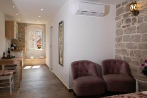 a living room with two chairs and a stone wall at Studio Amore in Diocletian palace in Split