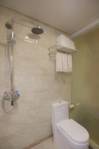 a bathroom with a toilet and a shower with towels at Zhangjiajie Wangyi Inn in Zhangjiajie
