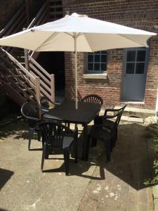une table et des chaises noires sous un parasol dans l'établissement Le Charlot, à Saint-Valery-sur-Somme