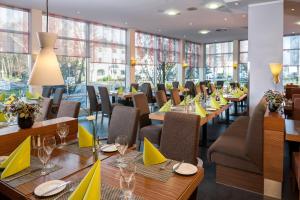 ケルンにあるEssential by Dorint Köln-Junkersdorfのテーブルと椅子に黄色のナプキンを乗せたレストランを併設しています。