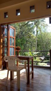 a wooden table and a white chair on a porch at Rura Raya Homestay in Rantepao