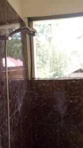 y baño con ducha y ventana. en Rura Raya Homestay en Rantepao