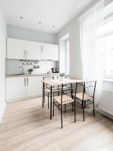 グディニャにあるMieszkanie w Ścisłym Centrum Gdyniの白いキャビネット、テーブルと椅子付きのキッチンが備わります。
