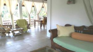 a living room with a couch and chairs and windows at Villa Jakaranda and Villa Marakuya in Lovina