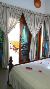 a bedroom with a bed with curtains and a mirror at Villa Jakaranda and Villa Marakuya in Lovina