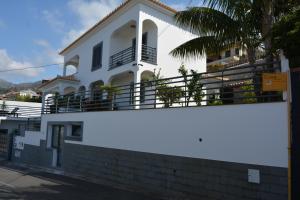 ein weißes Haus mit einem Balkon und einer Palme in der Unterkunft Sea and Sun 4 You - Choupana Studio in Funchal