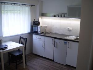 cocina con armarios blancos, mesa y microondas en Apartment Za Poštou, en Bělkovice