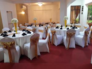 una sala banchetti con tavoli e sedie bianchi di The Kingston Hotel a Kiribathgoda