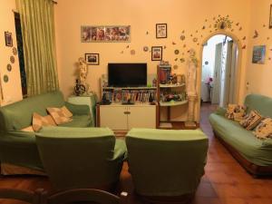 a living room with two green chairs and a television at B&B Le Mille E Una Notte in Olbia