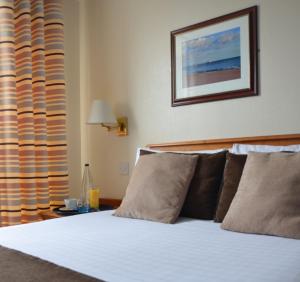 a bedroom with a white bed with pillows at The Riviera Hotel & Apartments - Alum Chine in Bournemouth