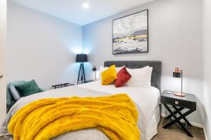 a bedroom with a bed with a yellow blanket on it at Chic Metro Apartment with Free Parking and Air-con in Auckland