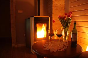 a table with two glasses and a bottle of wine and flowers at Na Dworosku in Golczowice