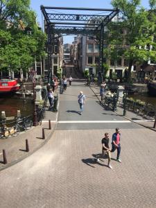 een groep mensen die op een stenen loopbrug naast een rivier zitten bij Bridge Inn in Amsterdam