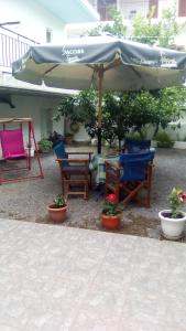 un patio con sillas, una sombrilla y una mesa en Studios Elpida, en Tyros