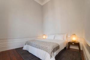 a white bedroom with a bed and two lamps at AD Apartment - Solar da Avenida in Porto