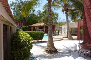 a courtyard with palm trees and a swimming pool at Hotel Grazia Maria in Saly Portudal