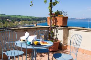 una mesa y sillas en un balcón con vistas al agua en La Dimora di Checchino, en Anguillara Sabazia