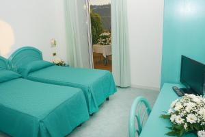 una camera d'albergo con due letti e una televisione di Hotel Capizzo a Ischia